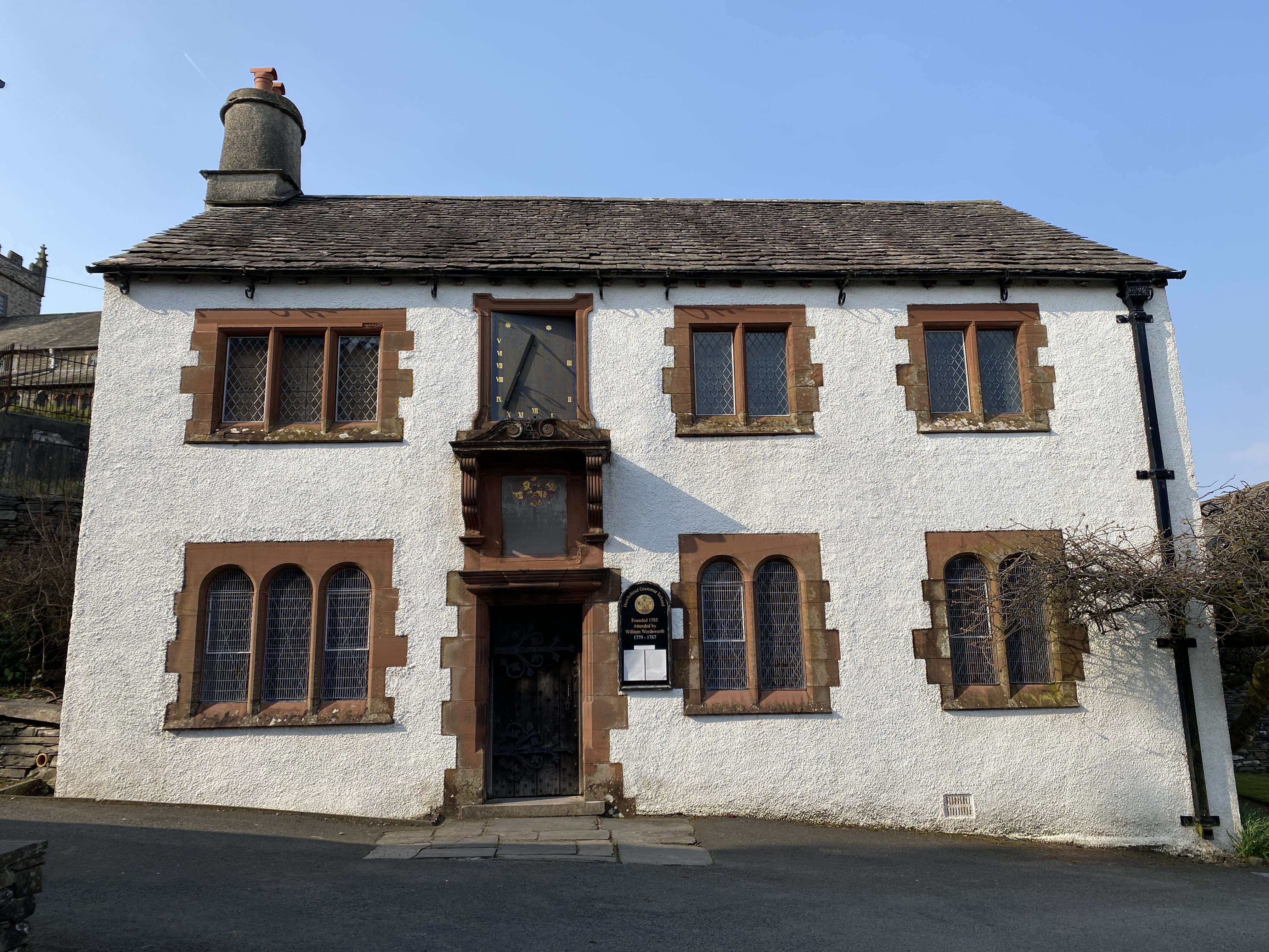 Photograph of Hawkshead Grammar School Exterior. A white building with a slate roof and red sandstone window frames 